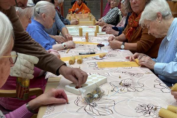Seniorinnen und Senioren stimmen sich bei der Kerzenherstellung auf Adventszeit ein